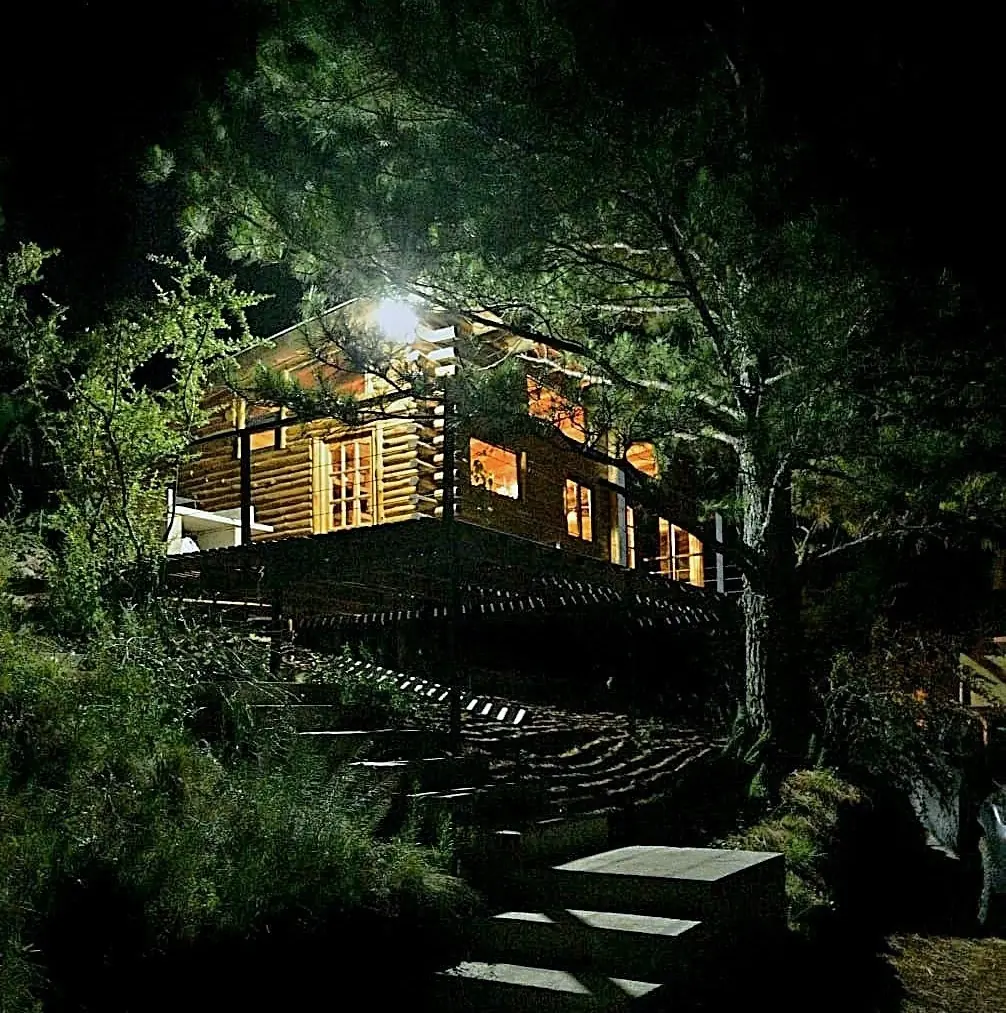 Cabaña iluminada de noche entre los pinos en Intiyaco, Córdoba