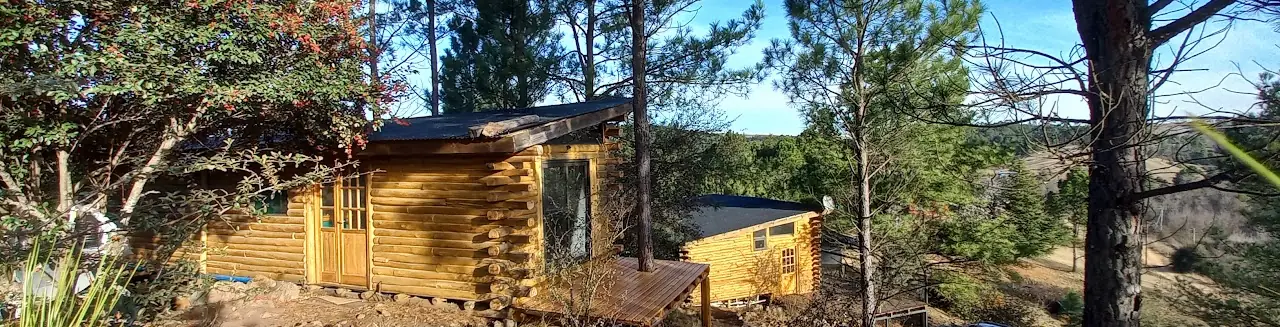 Vista panorámica de las cabañas entre pinos con las sierras de fondo en Intiyaco, Córdoba
